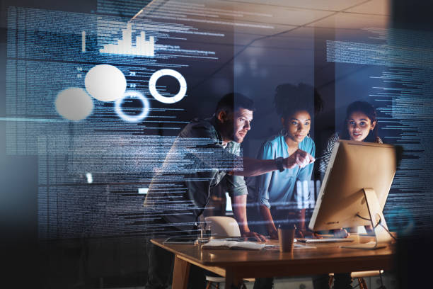 Taking on the late shift with true dedication Shot of a group of programmers working together on a computer code at night advanced business development stock pictures, royalty-free photos & images