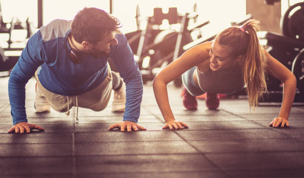 Push-ups i gym. We can do it together. Young smiling athletes exercising push-ups in a gym health club photos stock pictures, royalty-free photos & images