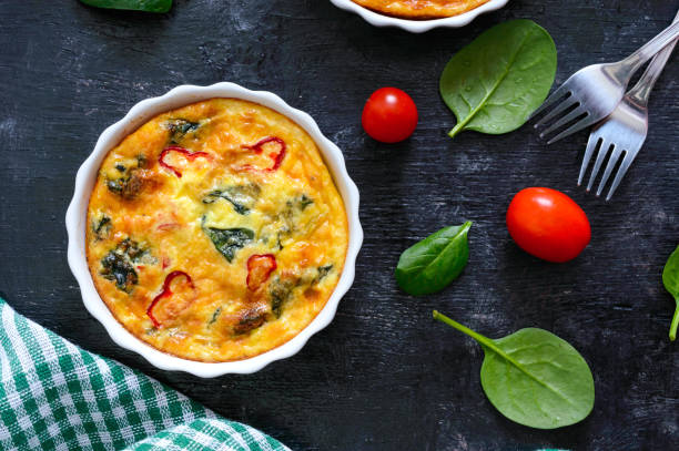 istock Frittata with fresh vegetables and spinach. Italian omelet in ceramic forms on a black background. Top view. 1081871764