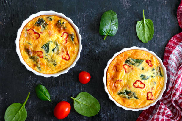 istock Frittata with fresh vegetables and spinach. Italian omelet in ceramic forms on a black background. Top view. 1081871774
