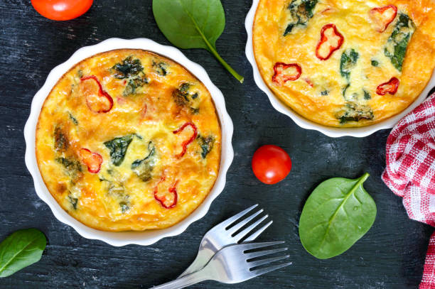 istock Frittata with fresh vegetables and spinach. Italian omelet in ceramic forms on a black background. Top view. 1081871780