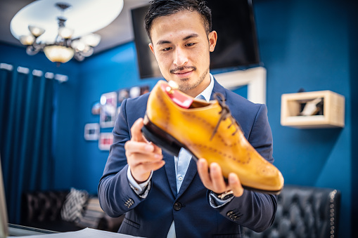 Chinese shoemaker checking a leather shoe carefully.