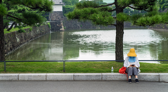 Tokyo, Japan - August 2018: Unidentified woman sitting by the pond of Imperial Palace, Tokyo, Japan