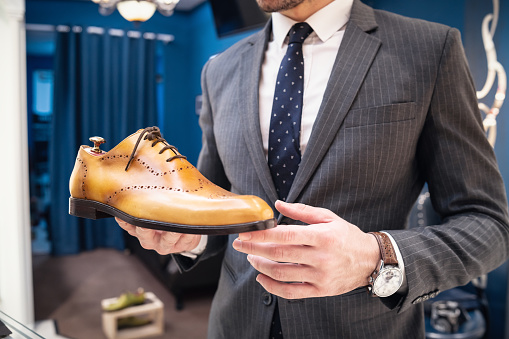 Young man holding an expensive leather shoe.