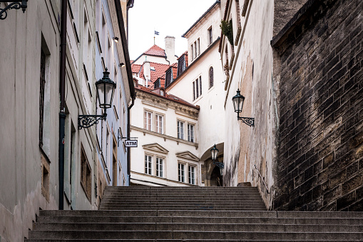 Color image depicting the streets of old town Prague, Czech Republic. In the distance there is a sign for an ATM machine (automated teller).