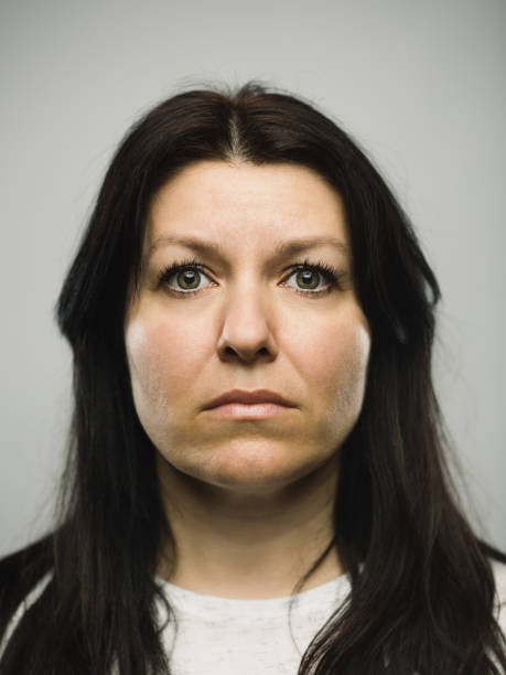 Real caucasian adult woman with blank expression Close up portrait of caucasian mature woman with blank expression against gray background. Vertical shot of real slovenian woman staring in studio with long dark hair and green eyes. Photography from a DSLR camera. Sharp focus on eyes. fine art portrait photos stock pictures, royalty-free photos & images