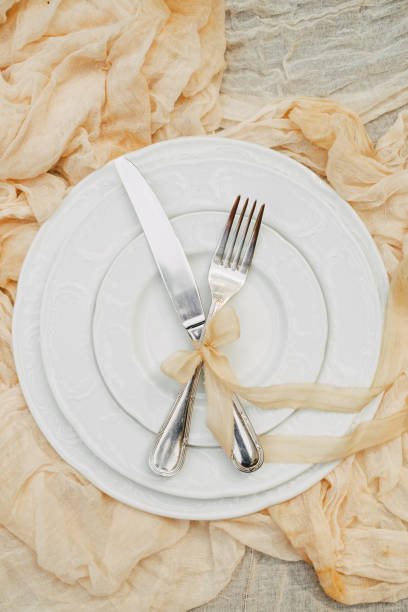 istock White plates, fork, knife and decoration on the background of a light fabric, wedding decor. view from above 1081885678