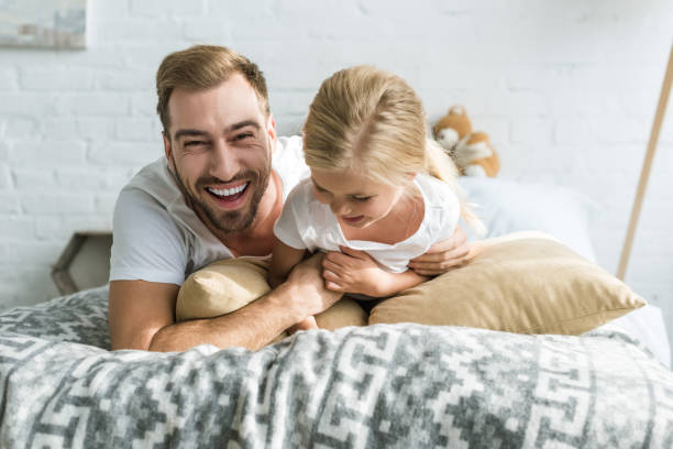 istock cheerful father and little daughter having fun together while lying on bed 1081886690