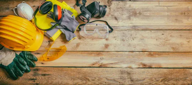 Photo of Construction safety. Protective hard hat, headphones, gloves and glasses on wooden background, banner