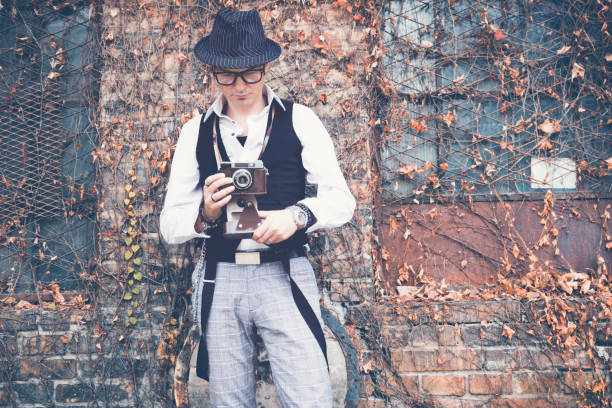 istock Retro styled man with vintage photo camera against brick wall. 1081887494