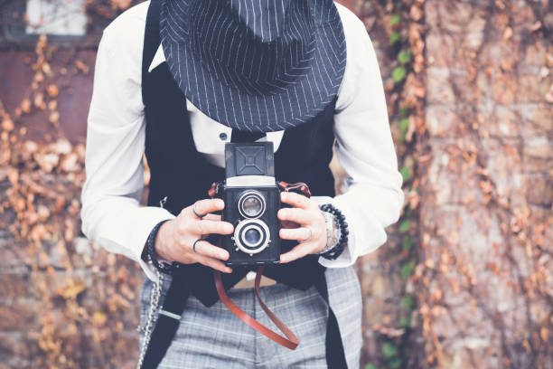 Unrecognizable photographer looking through visor and taking picture with vintage medium format photo camera.