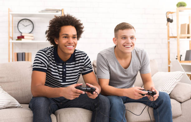 diversi ragazzi adolescenti che giocano a console di gioco a casa - teenager video game gamer child foto e immagini stock