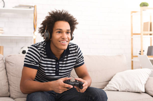 african-american teenager playing video games at home - people joy relaxation concentration imagens e fotografias de stock