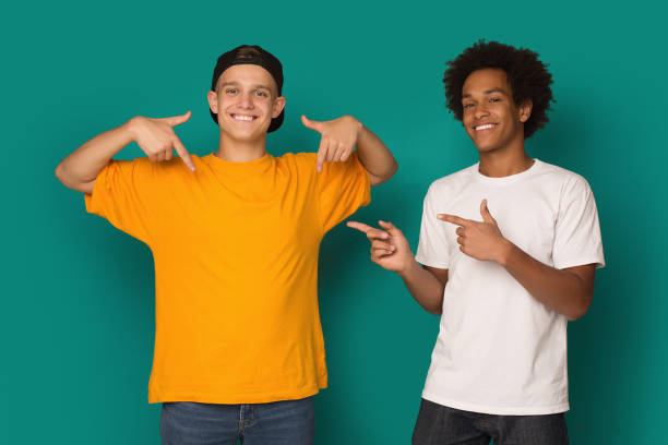 istock Diverse teens pointing at blank t-shirt over blue background 1081888972