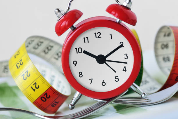 istock Forks holding alarm clock and meter on plate - Time to diet concept 1081889106