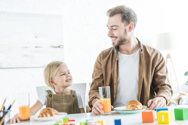 istock happy father and cute little daughter smiling each other while having breakfast together 1081891424