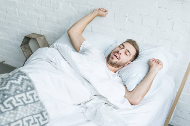 istock high angle view young man yawning and stretching in bed 1081891472