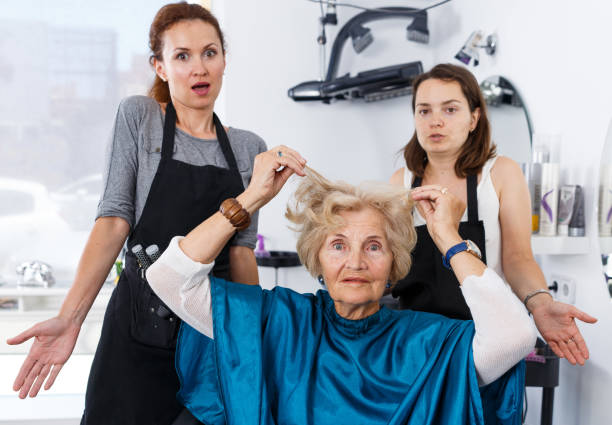 Shocked elderly female client at barbershop Portrait of shocked elderly female client with apologetic hairdressers at barbershop angry hairstylist stock pictures, royalty-free photos & images