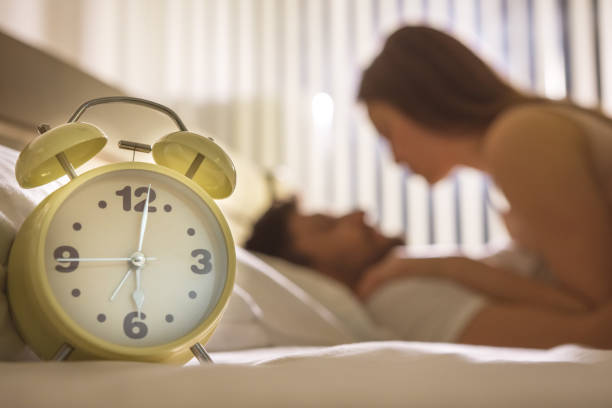 The clock on the background of the couple in the bed stock photo