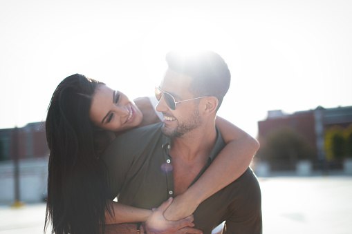 Happy young urban couple doing piggyback at outdoors, happiness