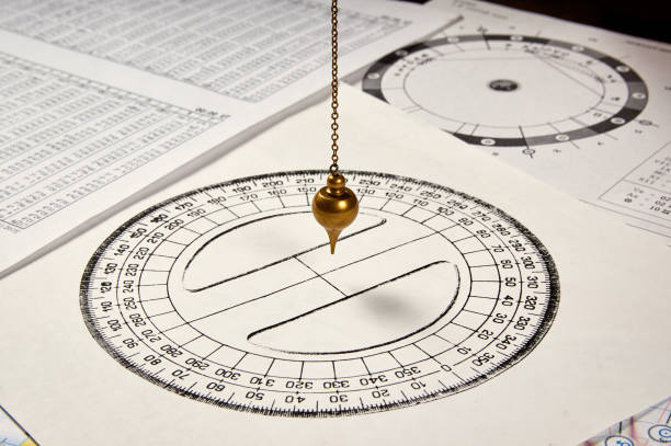 pendulum for divination Astrological pendulum for tarot and astrological circle on the background of astrological sheets pendulum stock pictures, royalty-free photos & images