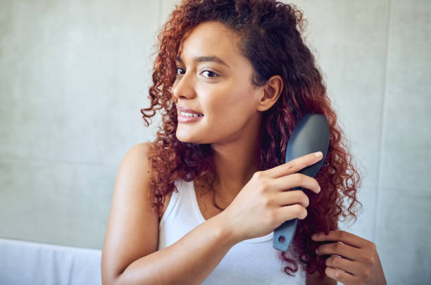 It you treat your hair, you'll never have bad hair days Cropped shot of a beautiful young woman brushing her hair in the bathroom at home brushing hair stock pictures, royalty-free photos & images