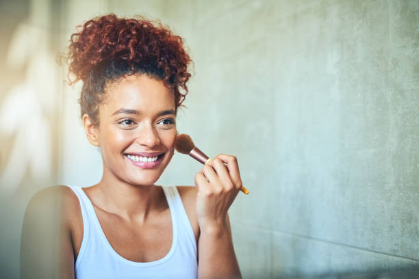 It's time to glow up! Shot of a young woman using a makeup brush while looking in her bathroom mirror blusher make up stock pictures, royalty-free photos & images