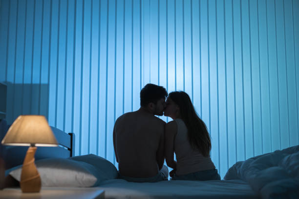 całująca się para siedzi na łóżku. połów nocny - quilt back zdjęcia i obrazy z banku zdjęć
