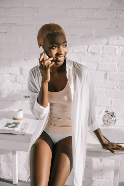 istock cheerful african american woman talking on smartphone in white kitchen 1081906814