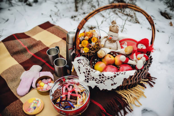 冬の公園で雪の装飾。クッキー、果物、ホット紅茶、コーヒー付きバスケット。森のピクニック毛布の上幸せな雪だるま。メリー クリスマスと新年挨拶のカードはコピー スペースを持つ。 - snow winter bench park ストックフォトと画像