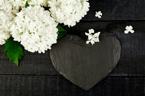 Bouquet flower hydrangea and slate heart on black wooden background