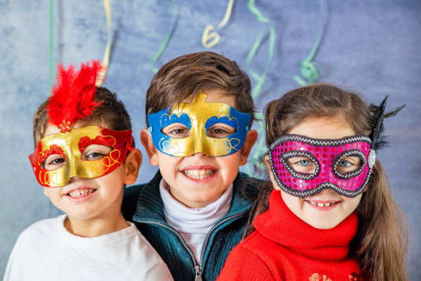A woman dressed in a witch costume applies temporary spooky tattoos to children during a Halloween celebration. The kids, wearing colorful costumes, enjoy the playful activity as part of the festive party atmosphere.