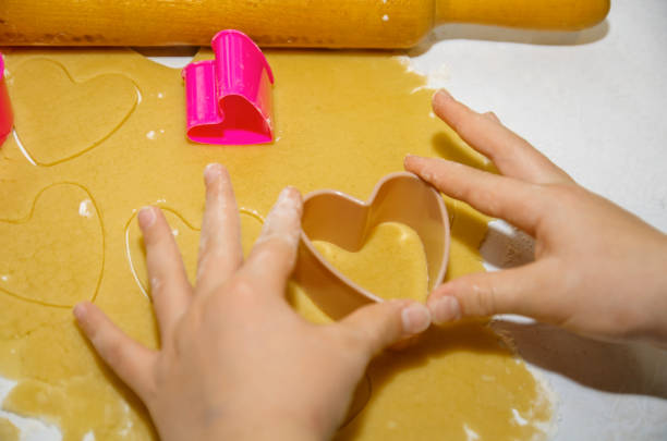 istock Hands making cookies from the dough using cookie cutters in the shape of a heart 1081912242