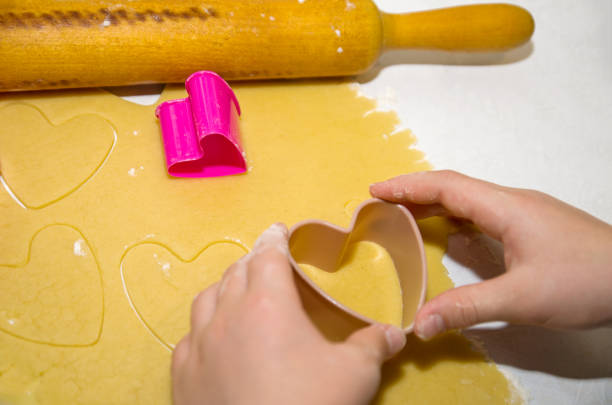 istock Two hands making cookies from the dough using cookie cutters in the shape of a heart 1081912268