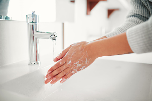 Cropped shot of a woman washing her hands in the bathroom at home