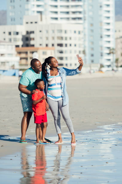 istock Family on beach taking selfie at water's edge 1081917612