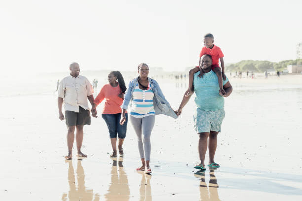 istock Family walking along wet sandy beach holding hands 1081917670