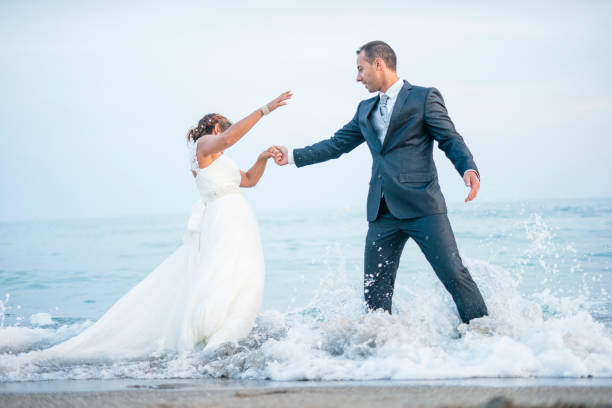 istock Groom rescuing the bride from waves 1081926180
