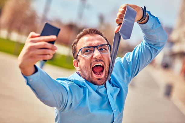 istock Funny businessman getting angry while using smartphone outdoors. 1081932116