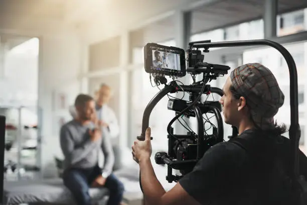 Behind the scenes shot of a camera operator shooting a scene with a state of the art camera inside of a studio during the day