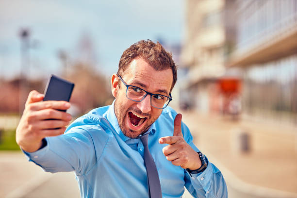 istock Funny businessman with thumbs up while using smartphone outdoors. 1081937074