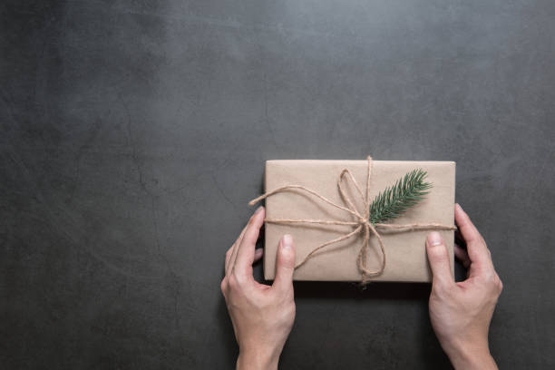 istock Man hands holding craft paper gift box on concrete background. 1081940086