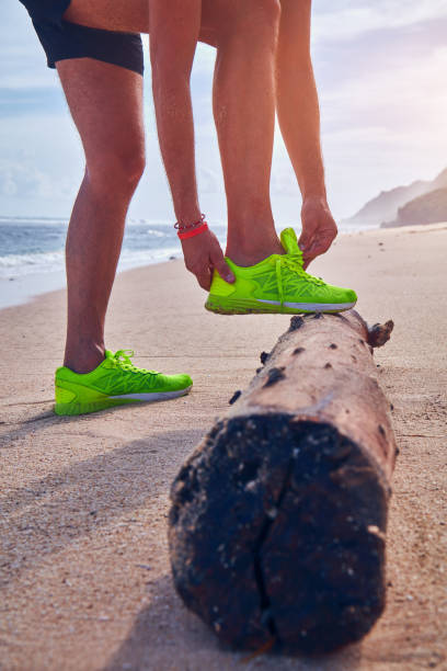 istock Man tying running sneakers on a tropical exotic beach. 1081941272