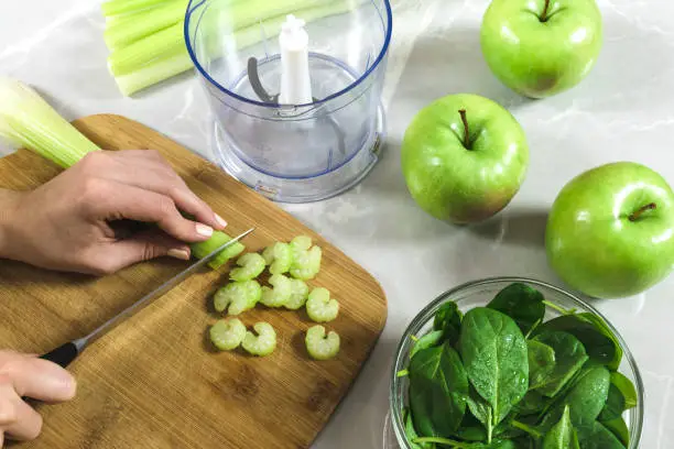 Smoothie preparation from celery, apples and spinach.