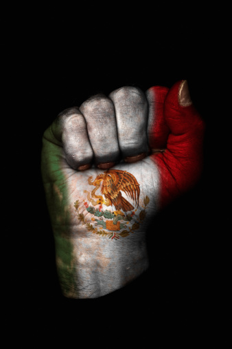 Image of a dirty clenched fist with the flag of Mexico painted on it.