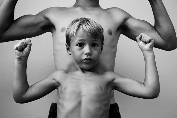 petit garçon contracter les muscles comme son frère derrière lui - child human muscle flexing muscles little boys photos et images de collection