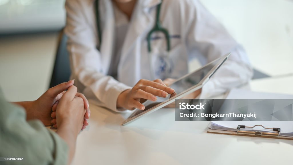 デジタル タブレットの患者にいくつかの情報を示す医師のショット - 医師のロイヤリティフリーストックフォト