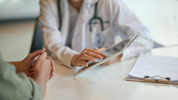 shot of a doctor showing a patient some information on a digital tablet - medico consultorio imagens e fotografias de stock
