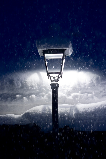 Evening street lighting. Three retro-style circular outdoor lights provide a beautiful white light. There is snow on top