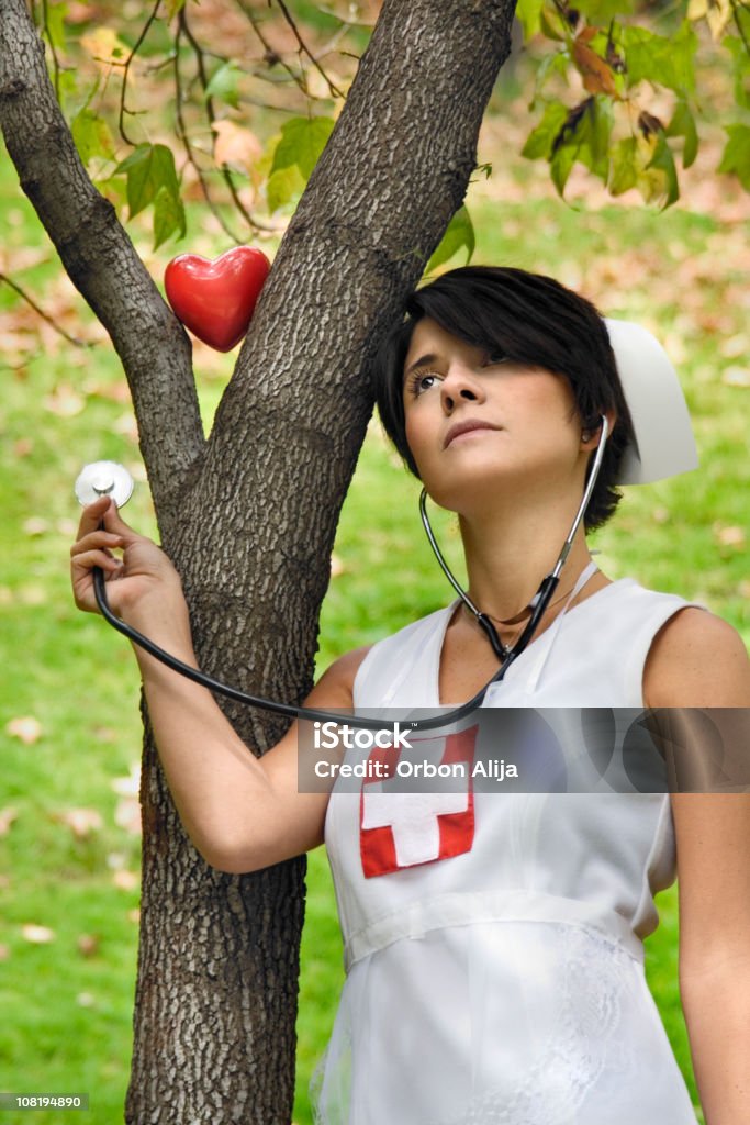 Infirmière femme vérifiant le cœur d'arbre avec stéthoscope - Photo de Examiner libre de droits